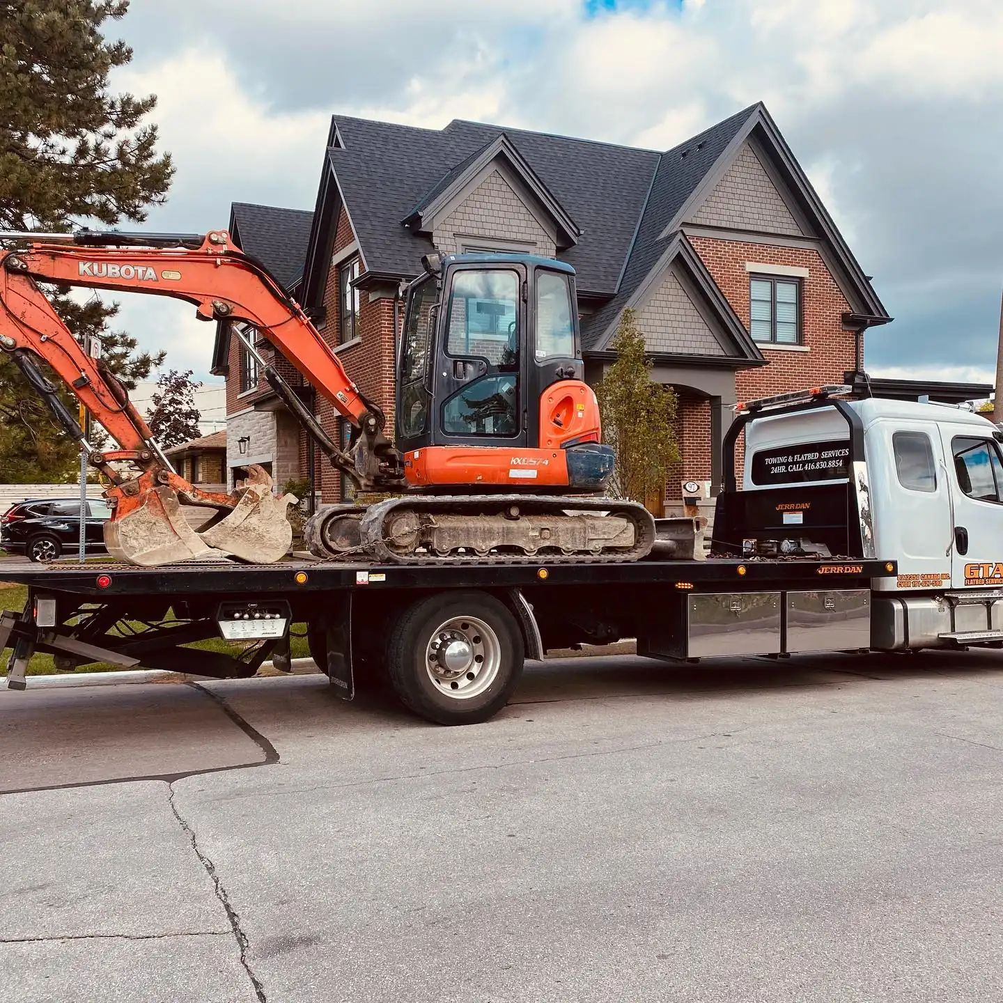 Mini excavator transported on a flatbed truck to a residential site